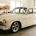 Rafraîchir l’apparence d’une voiture ancienne : 7 interventions utiles Voiture ancienne propre et brillante dans un garage lumineux, avec des jantes rénovées et une ambiance d’atelier soignée.